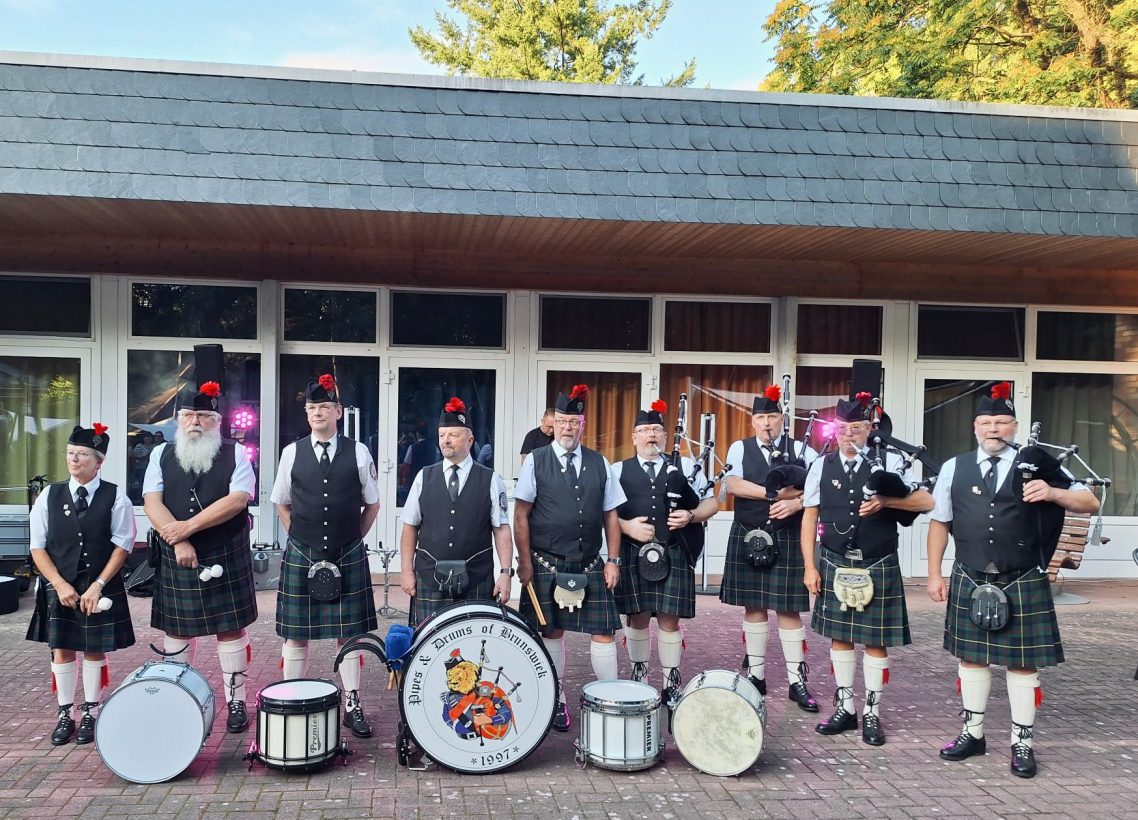 Schottische Musiker in traditioneller Kleidung mit Dudelsäcken und Trommeln.